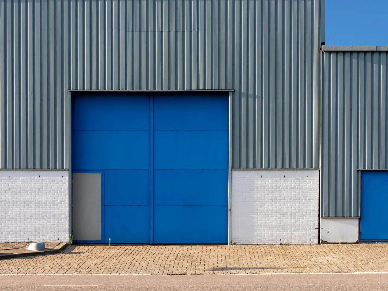 Corrugated steel industrial shed exterior with large blue access doors